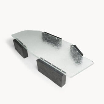 Elite coffee table with Moltrasio stone base, translucent glass top, palladium‑finished brass studs, black metal rail