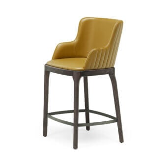 Luxury Magda Barré stool with smooth satin‑finish mustard‑yellow upholstery, dark wood frame, and matte‑grey metal footrest