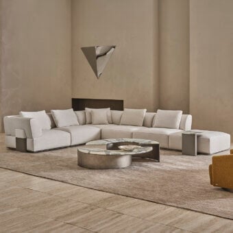 Contemporary Rugiano Hatton sectional with low-profile, off-white textile upholstery, leather-wrapped base, marble side tables
