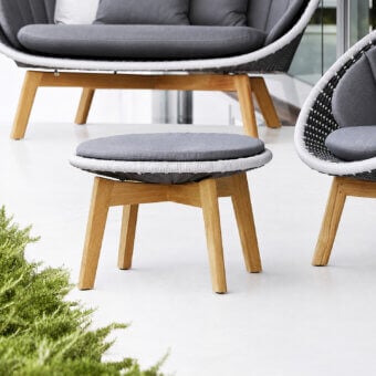 Sophisticated Cane-Line Peacock stool with grey textile cushion, white rim, and light-brown tapered wooden legs