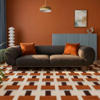 Luxury Egoitaliano Aster sofa with dark brown textured fabric, orange accent cushions, and epoxy powder coated metal frame