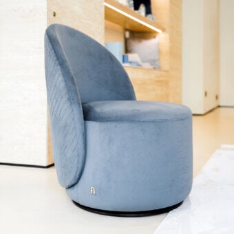Refined Furla Casa Venus swivel lounge chair in dusty blue fabric with V-shaped quilted detail and matte black metal base