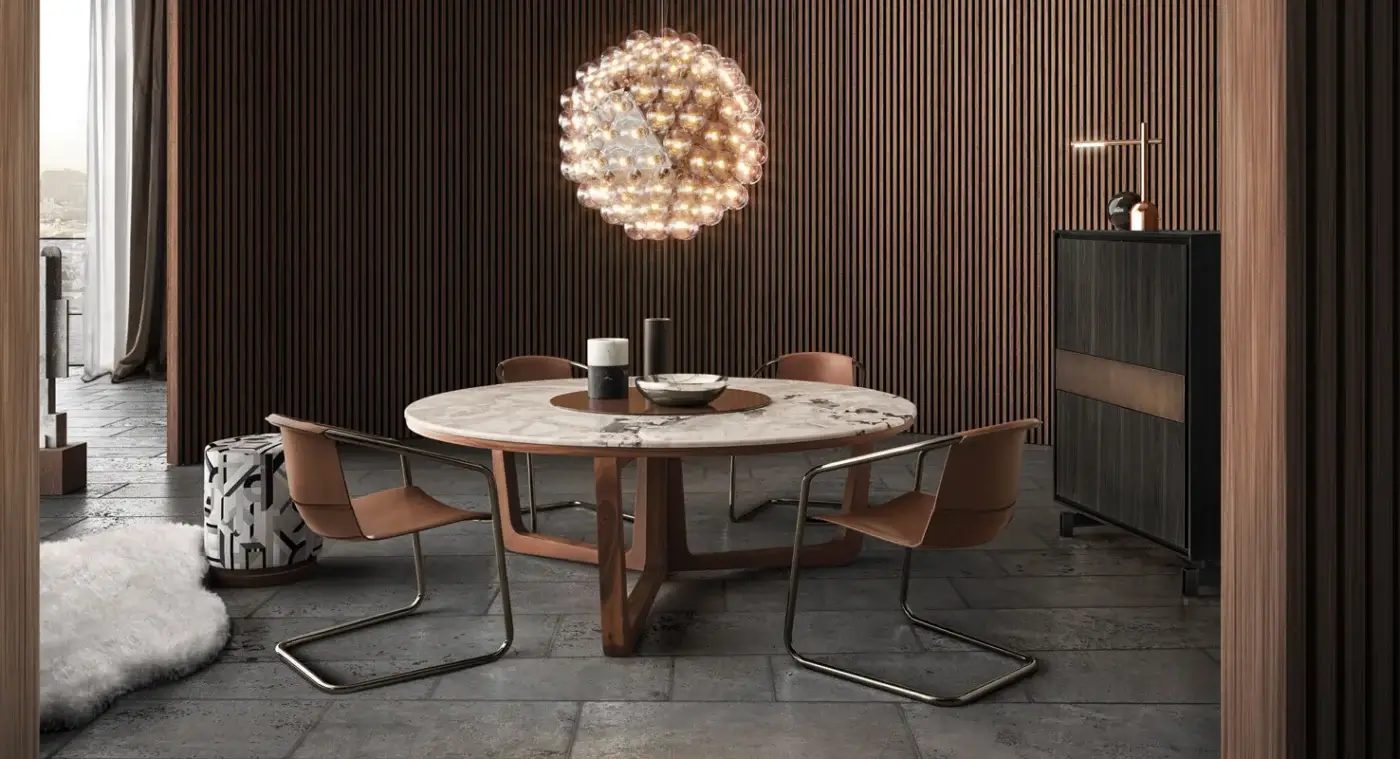 Round marble dining table with flared wood base, six tan leather mid-century chairs, and spherical glass orb chandelier in wood-paneled room.
