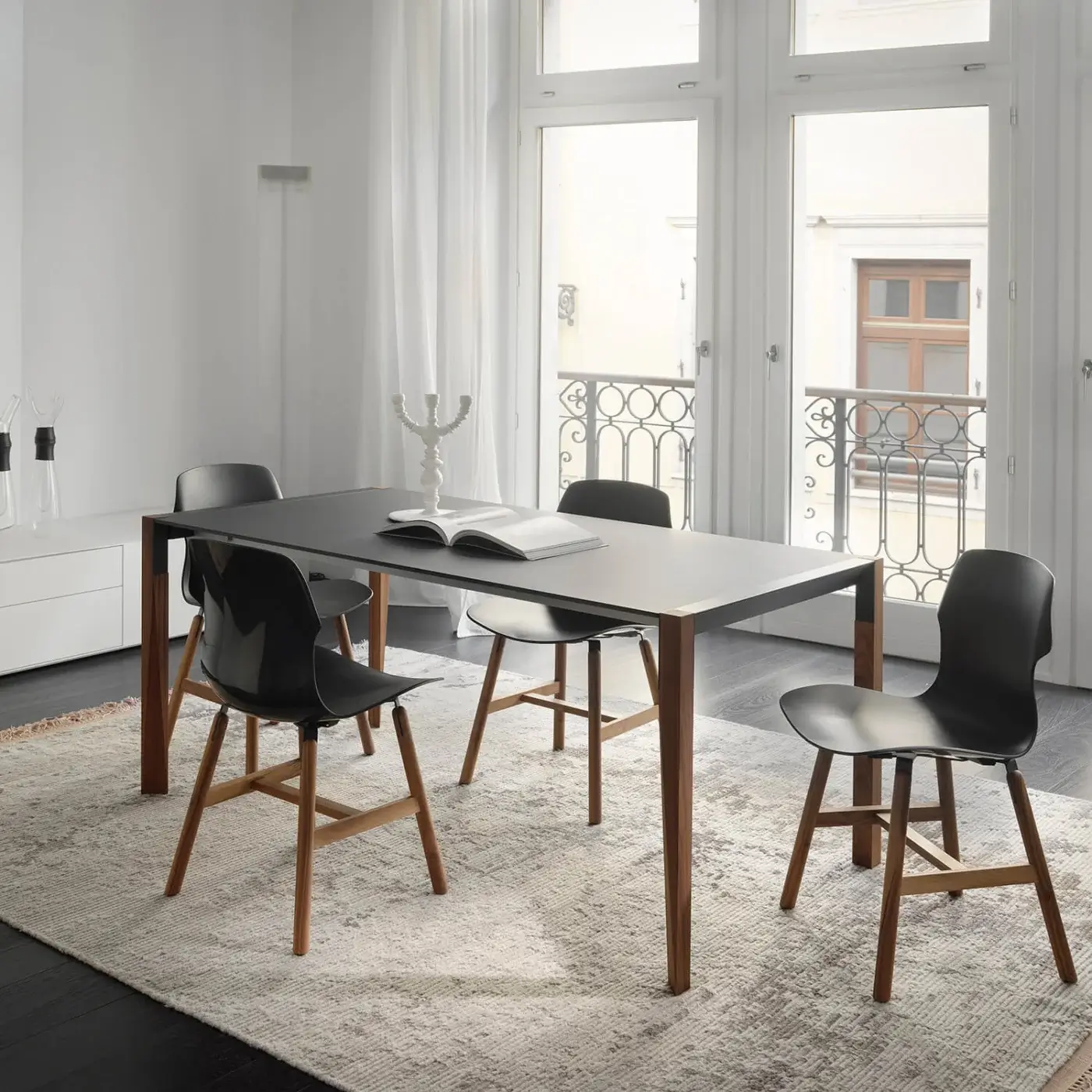Innovative Horm Tango table with a dark matte surface and sinuously shaped natural-toned wooden legs crafted in Italy