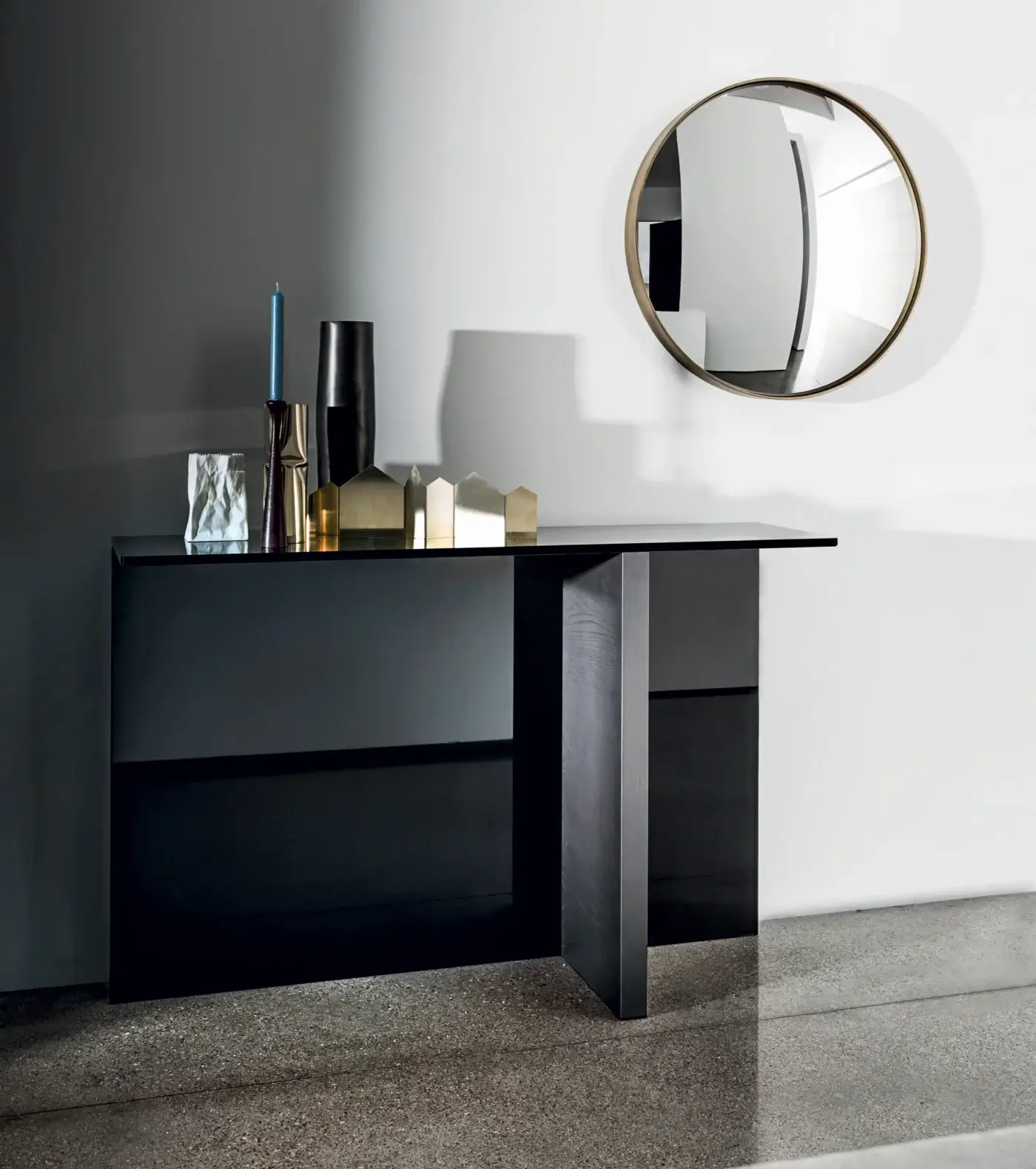 Black console table with concrete top, featuring silver decor, brass sculptures, and a Sail Mirror by Sovet Italia on a polished concrete floor.