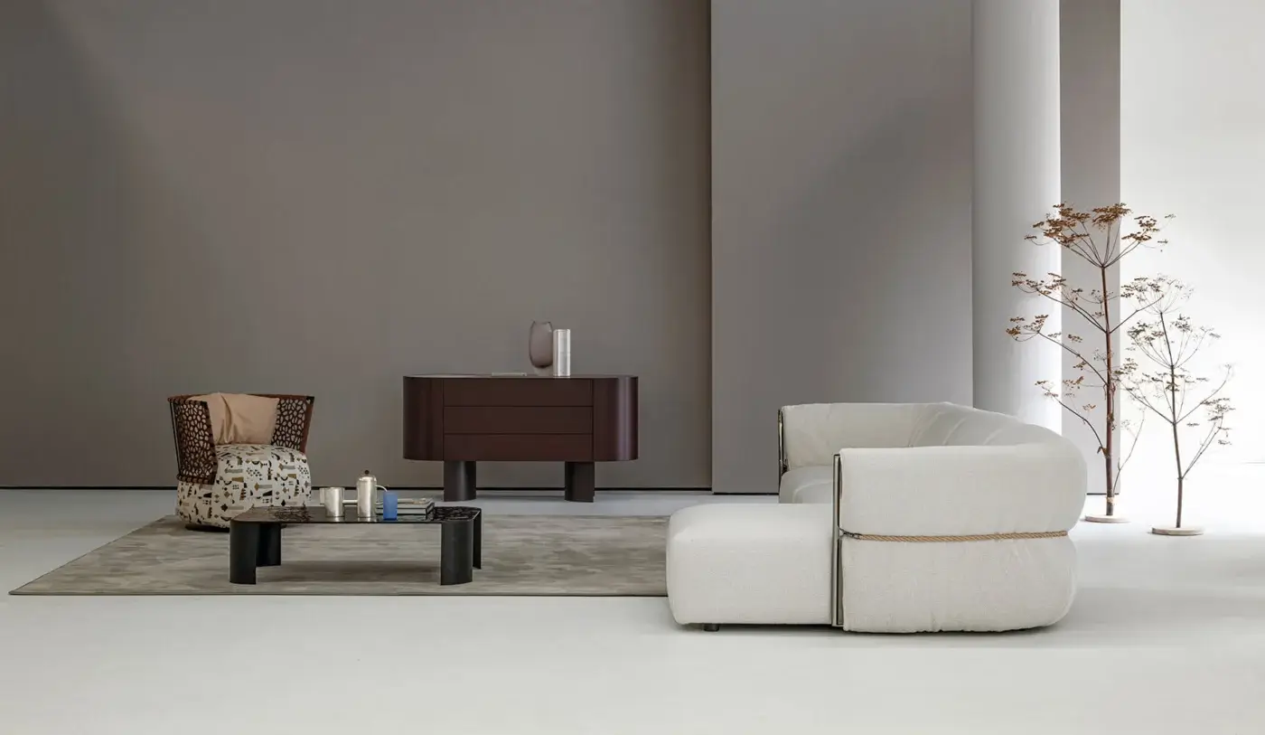 Beige Cierre 1972 sectional sofa with a dark brown leather belt detail, low profile, and rounded armrests in a minimalist living room.