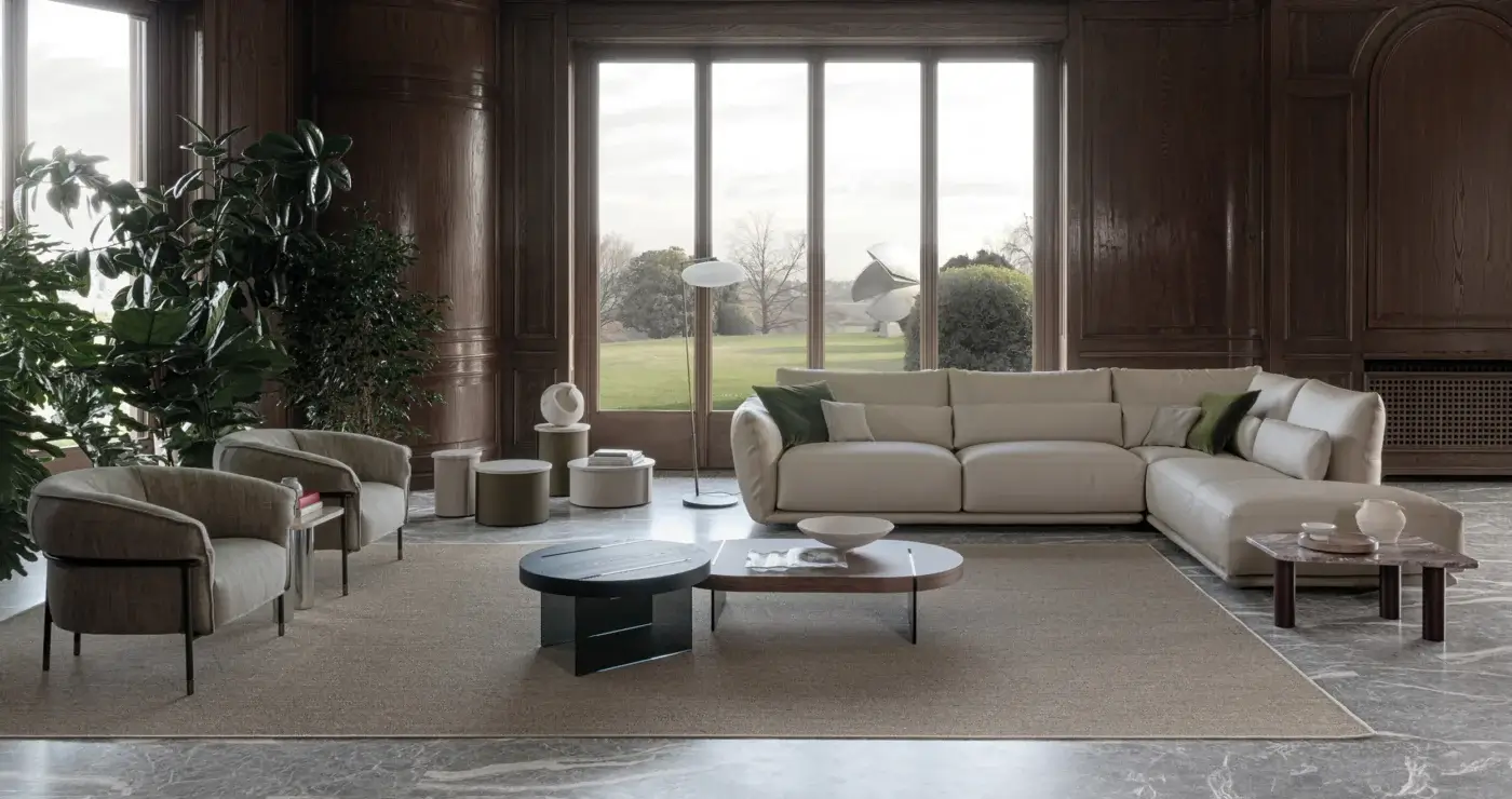 Cierre 1972 sectional sofa, light beige leather, modular chaise lounge, paired with dark metal armchairs and cylindrical side tables.