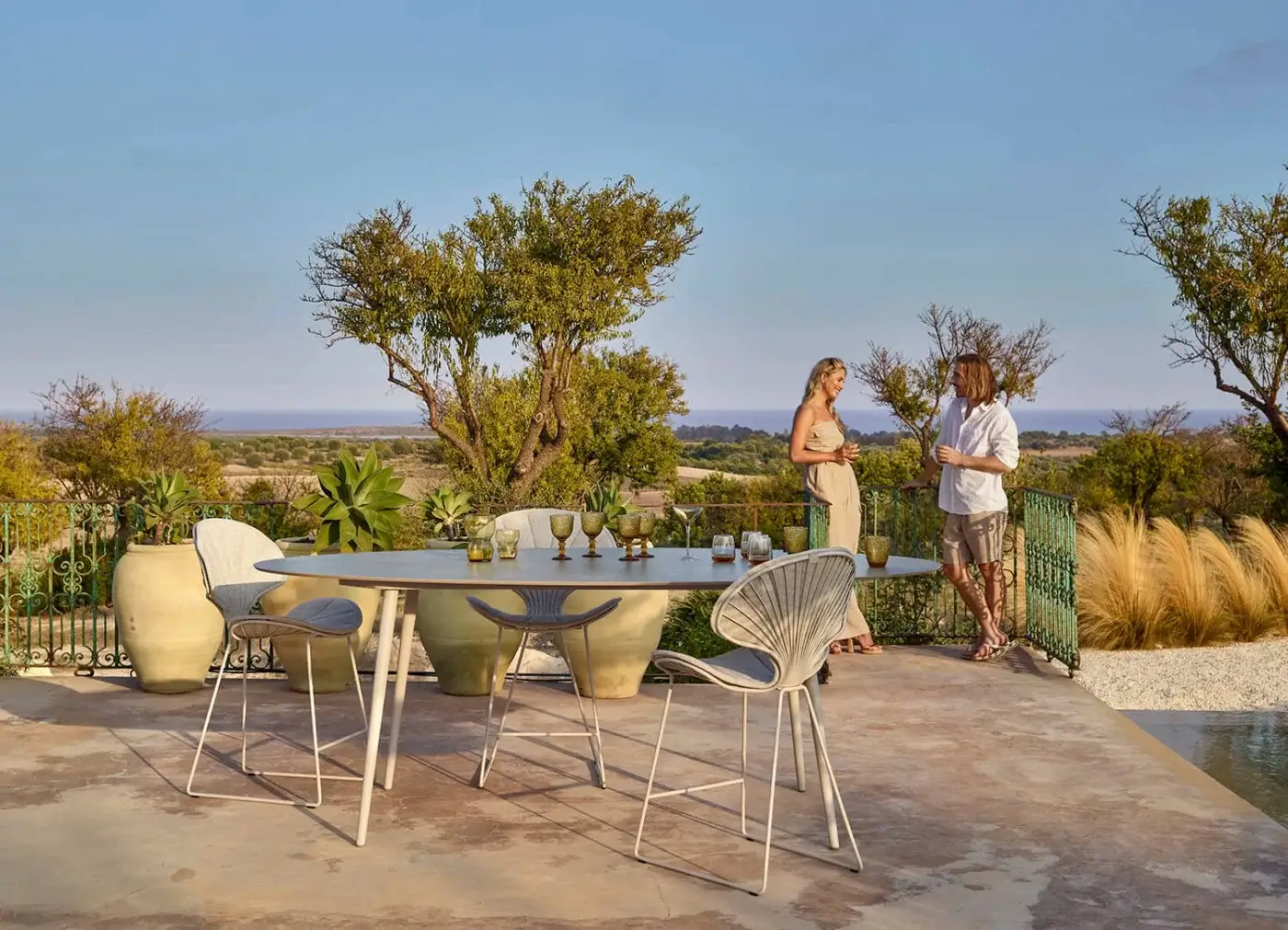 Elegant Royal Botania Styletto table stool with oval teak wood top and light grey woven material in matte white coated aluminum
