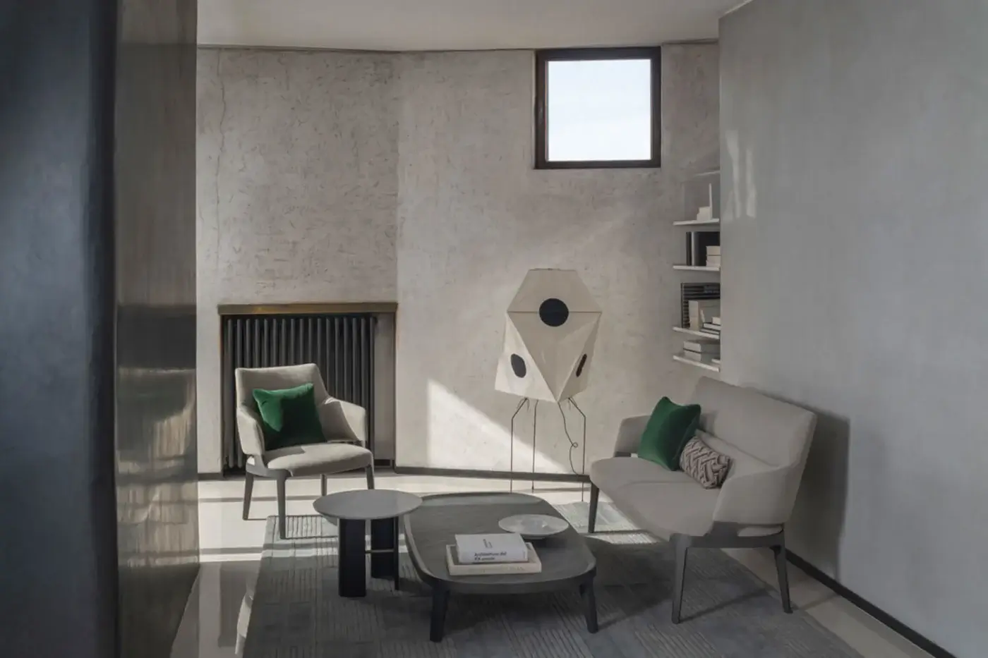 Velis sofa by Potocco, light gray fabric, low profile with curved back; green cushions, gray rug, geometric floor lamp, and book on coffee table.