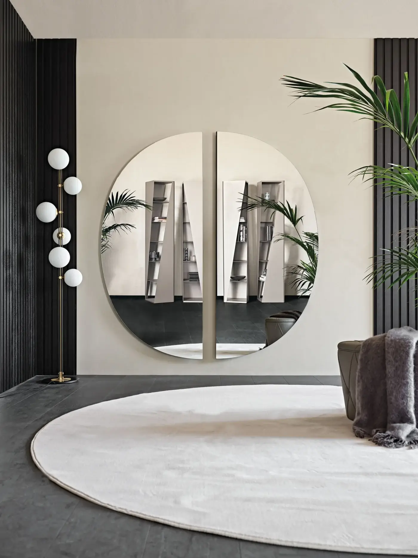 Day mirror, silvered glass, circular design, mounted on beige wall with wood slat accents, gold floor lamp, gray rug, and palm plant.