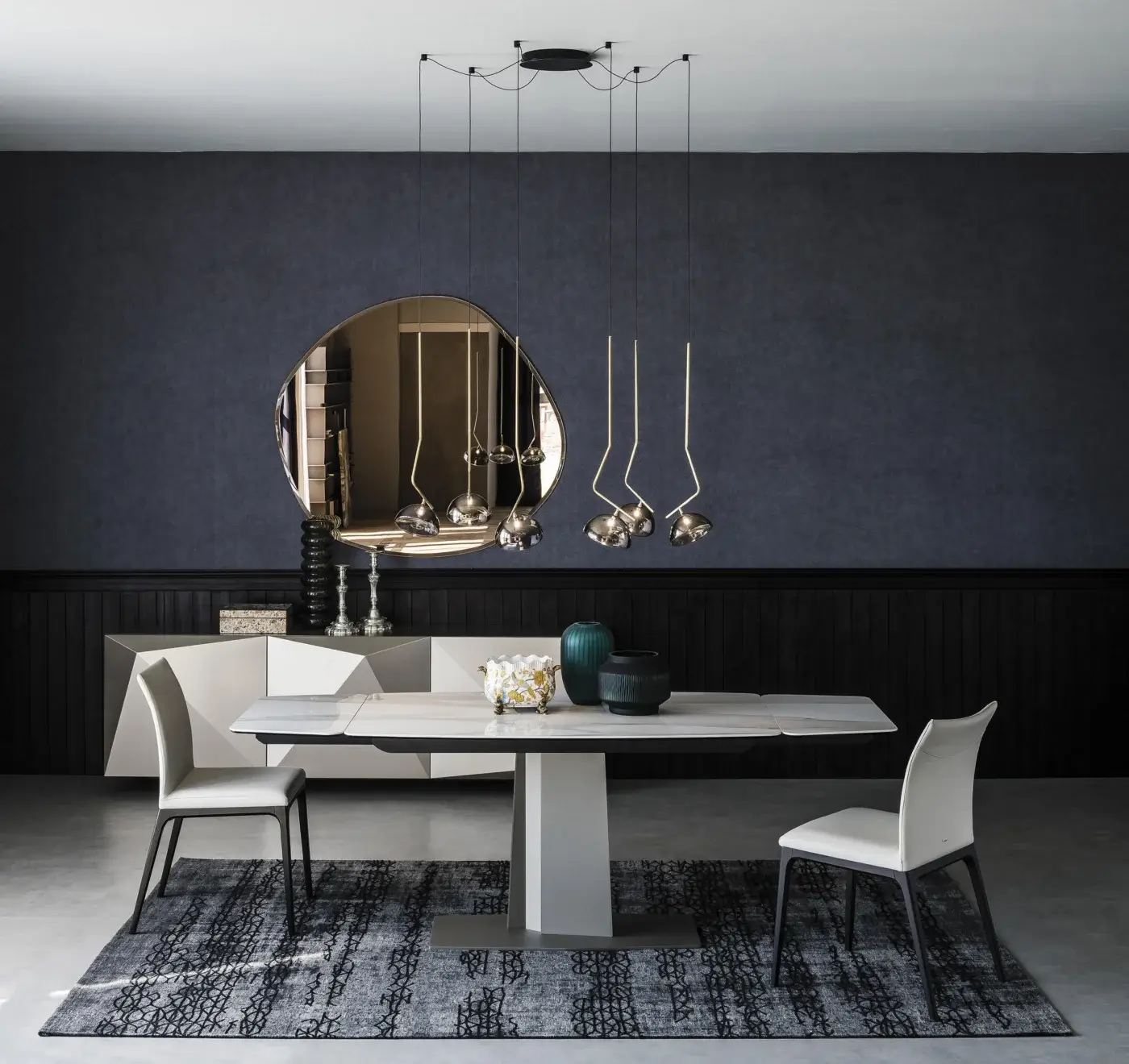 Grey ceramic Cattelan Italia Duffy table with white geometric pedestal, surrounded by four white upholstered dining chairs, in a modern room setting.