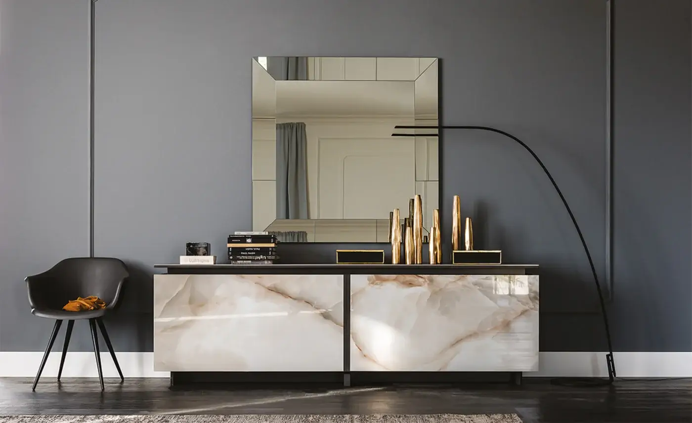 Cattelan Italia sideboard, ceramic top, beige veining, black body, rectangular mirror above, books & gold cylinders displayed on surface.