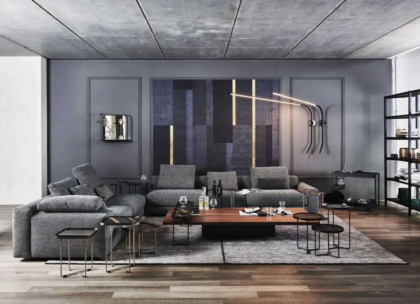 Walnut coffee table with black matte base, set on gray rug with brass side tables, facing a modular gray sofa in a modern living room.