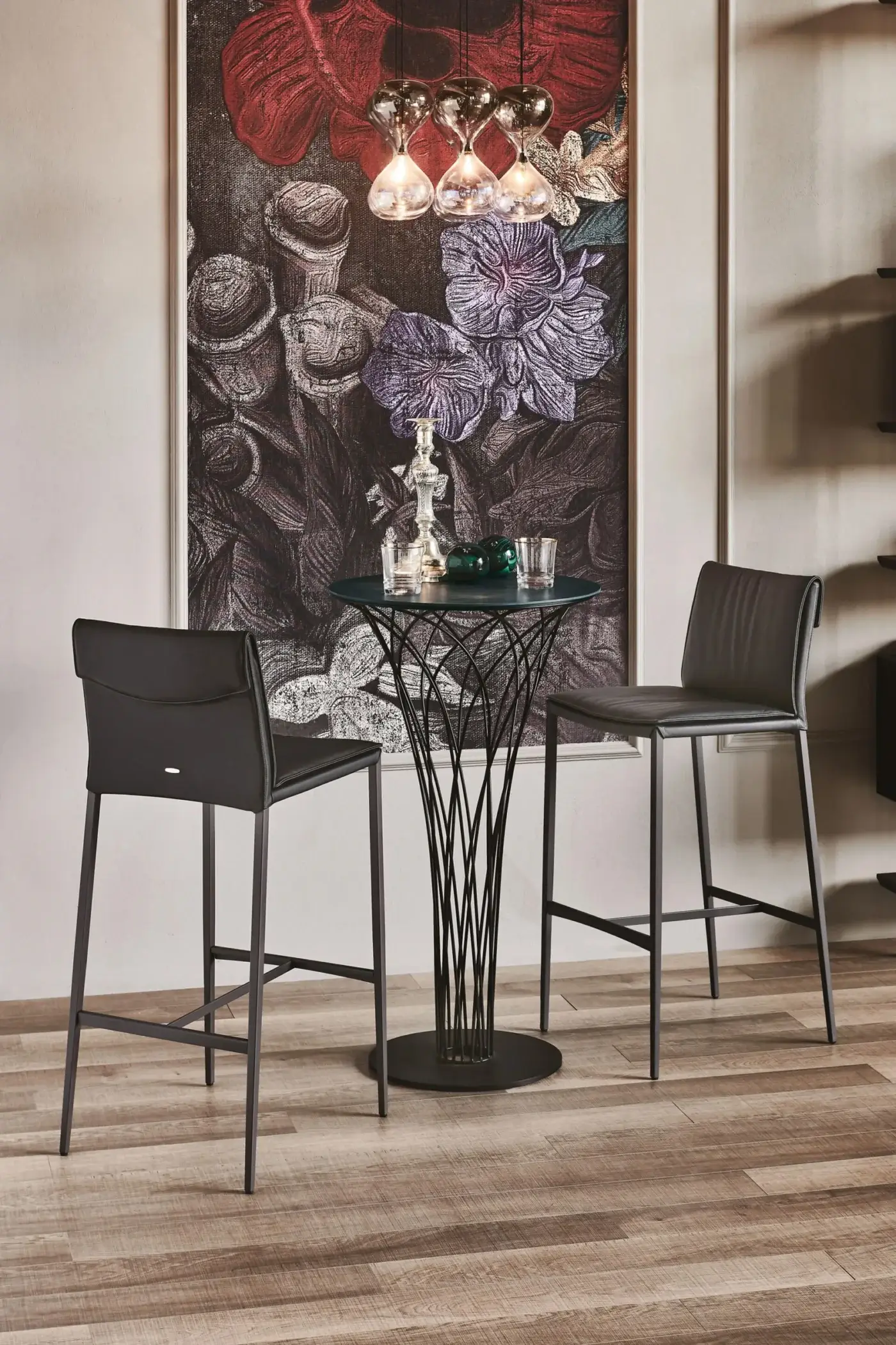 Cattelan Italia Isabel ML stools with black leather seats and matte black metal legs around a dark green glass table with openwork base.