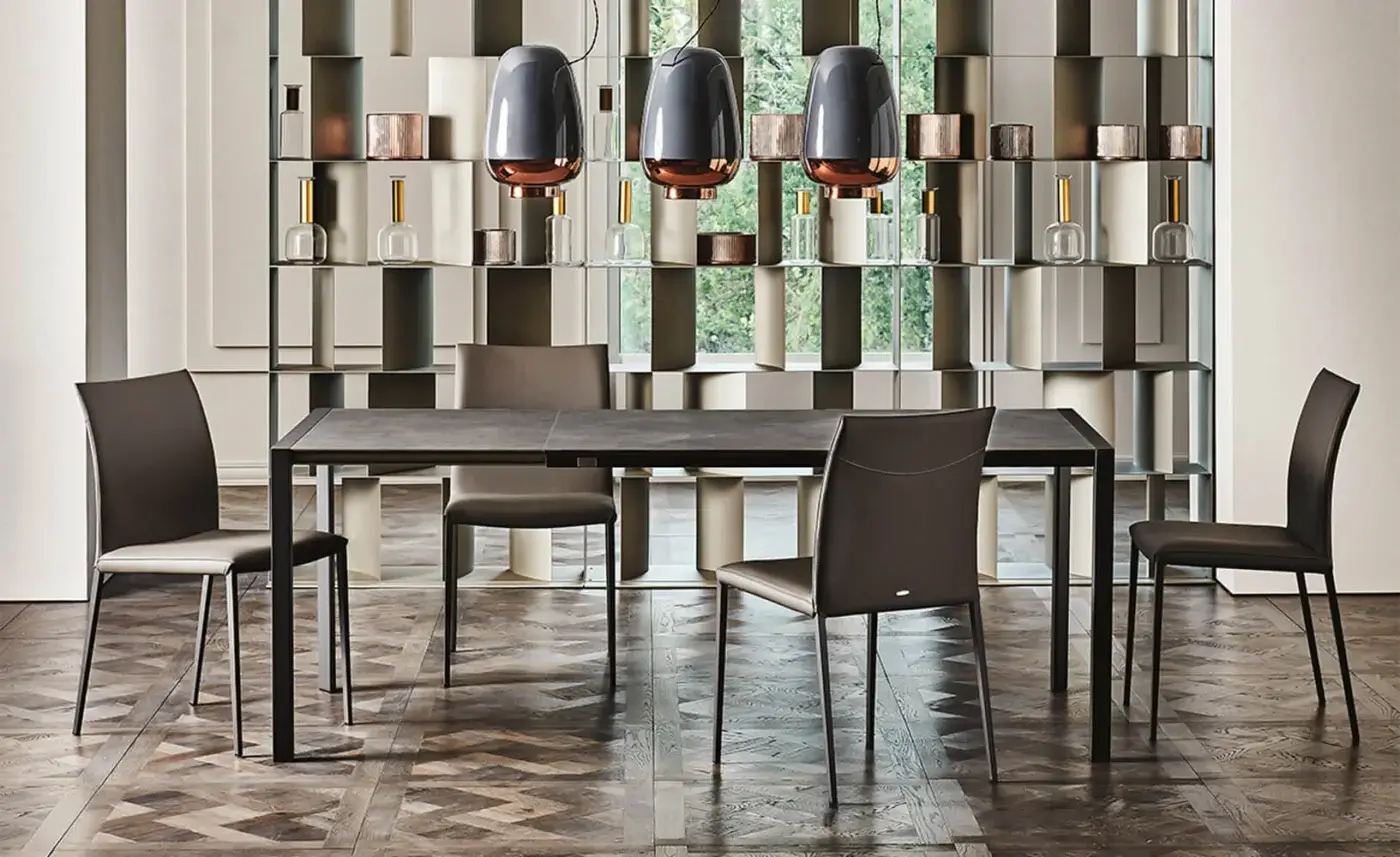 Dining room with gray concrete table, brown leather chairs, and three Cattelan Italia Asia lamps above herringbone wood floor.