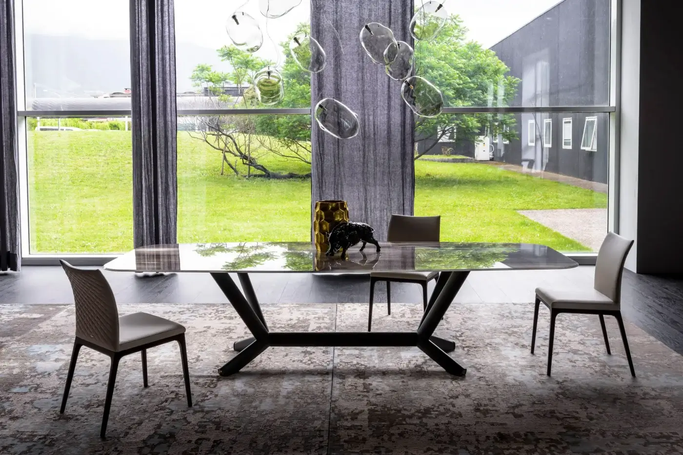 Cattelan Italia Planer table, dark gray glass top, angular dark wood base, modern dining chairs, neutral rug, contemporary interior.