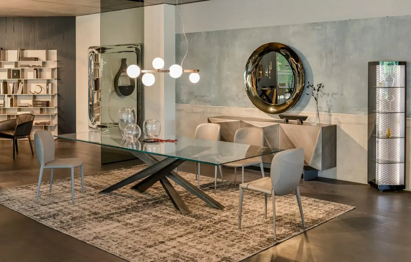 Cattelan Italia Lancer dining table, clear glass top, dark grey metal starburst base, modern dining room setting with rug and sideboard.