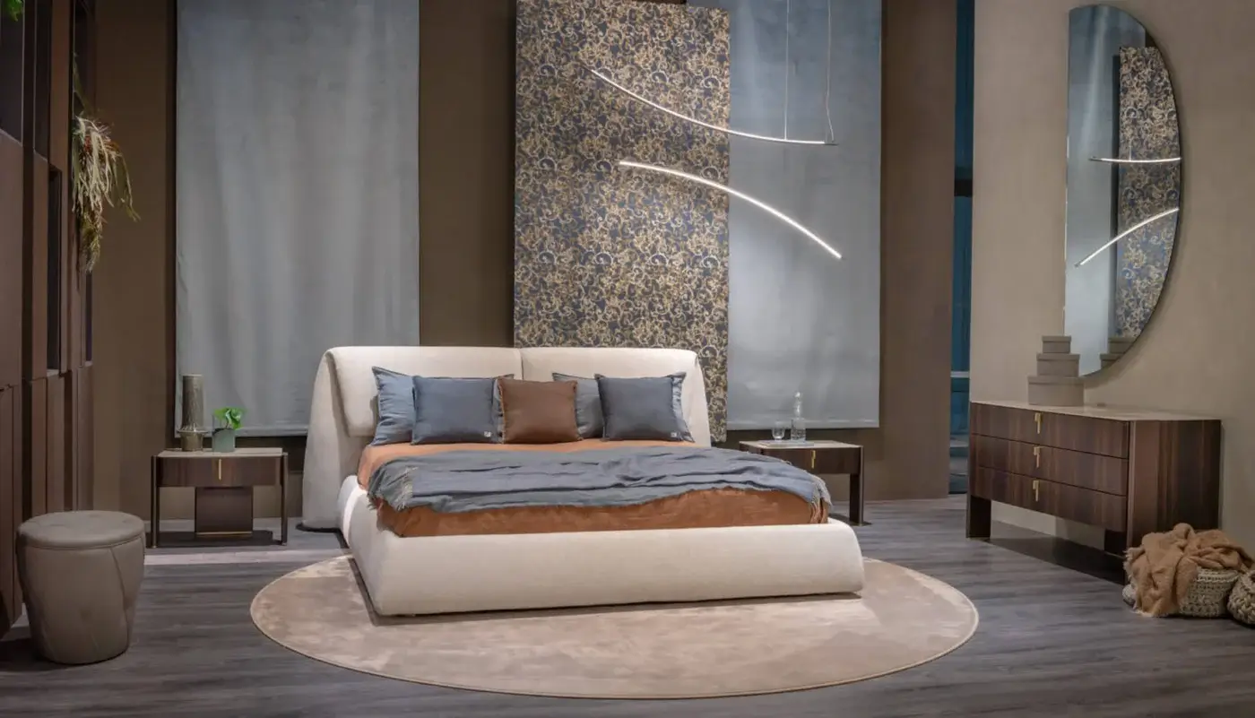 Cattelan Italia Simon bed, beige upholstered headboard, rust throw, blue pillows, dark wood nightstands, oval mirror, patterned wallpaper.