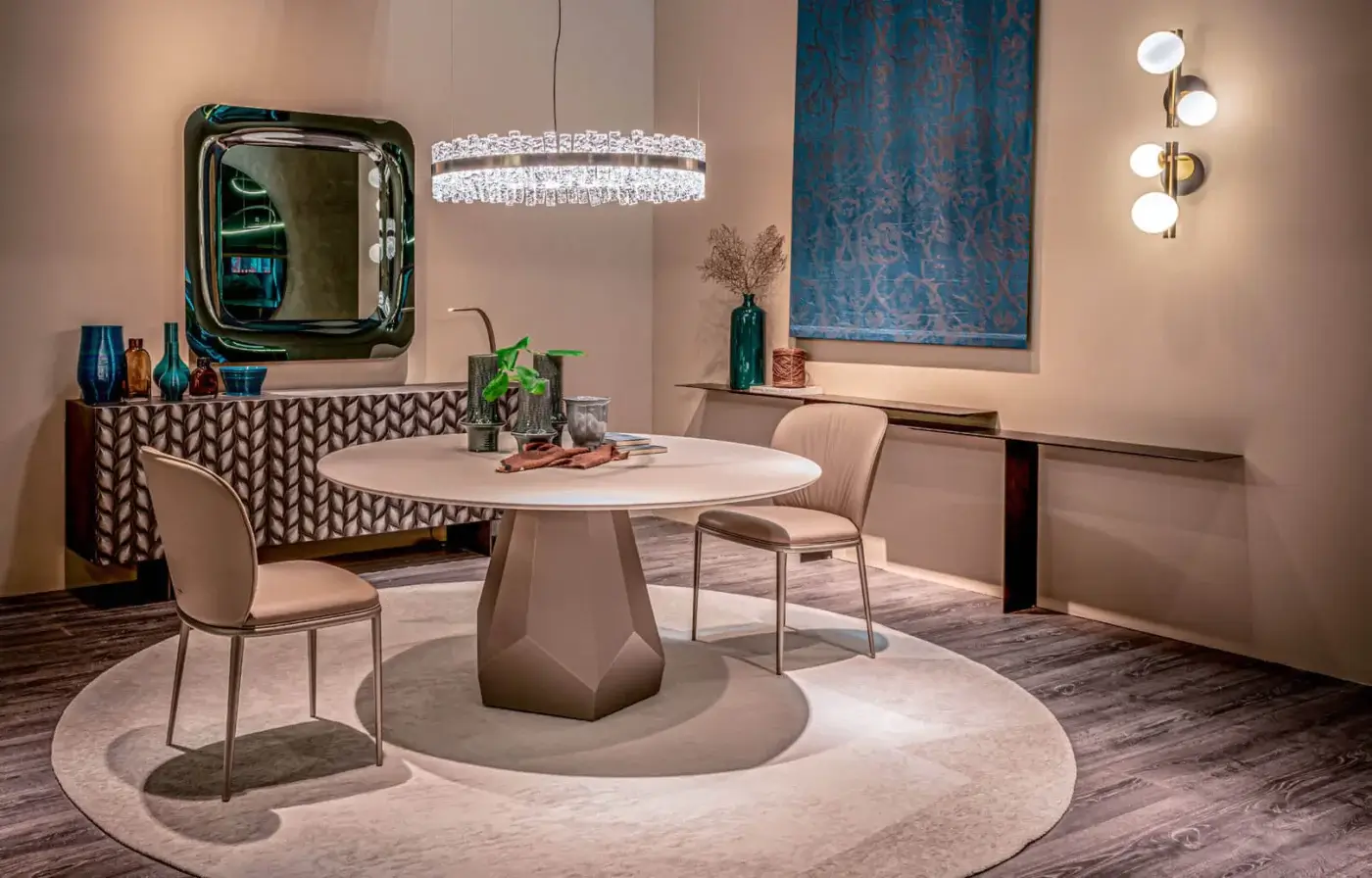 Cattelan Italia Zermatt dining table with light grey matte top and faceted base, surrounded by beige leather chairs on a cream rug.