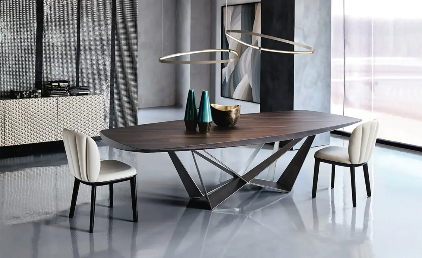Walnut Skorpio table with brushed metal X-base, gray fabric chairs, and gold pendant lights in a modern dining room setting.