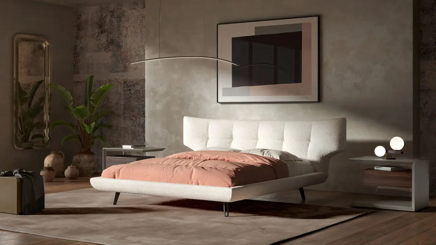 Cattelan Italia bed, beige upholstery, curved headboard with dark metal legs, coral duvet, wood dresser, arched gold mirror, gray bedside table.