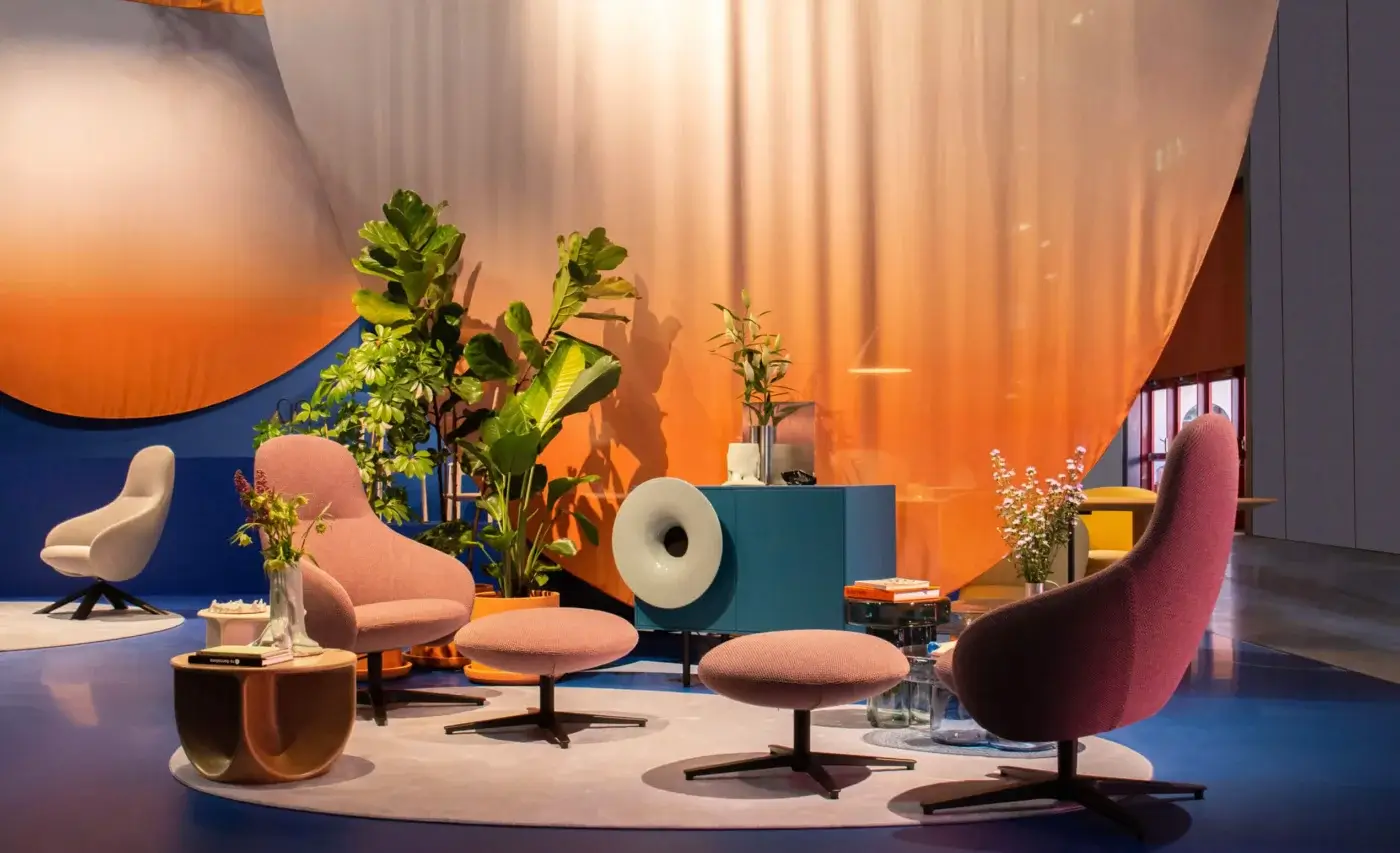 Nebula Alu Lounge Chairs, dusty rose fabric, rounded swivel design, on gray rug with orange fabric panels and teal console table.