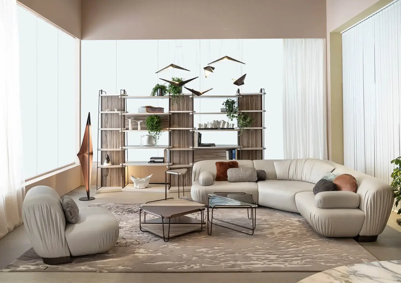 Beige leather lounge chair and curved sectional sofa with patterned rug, wood shelving, bronze fixtures, and neutral color scheme.