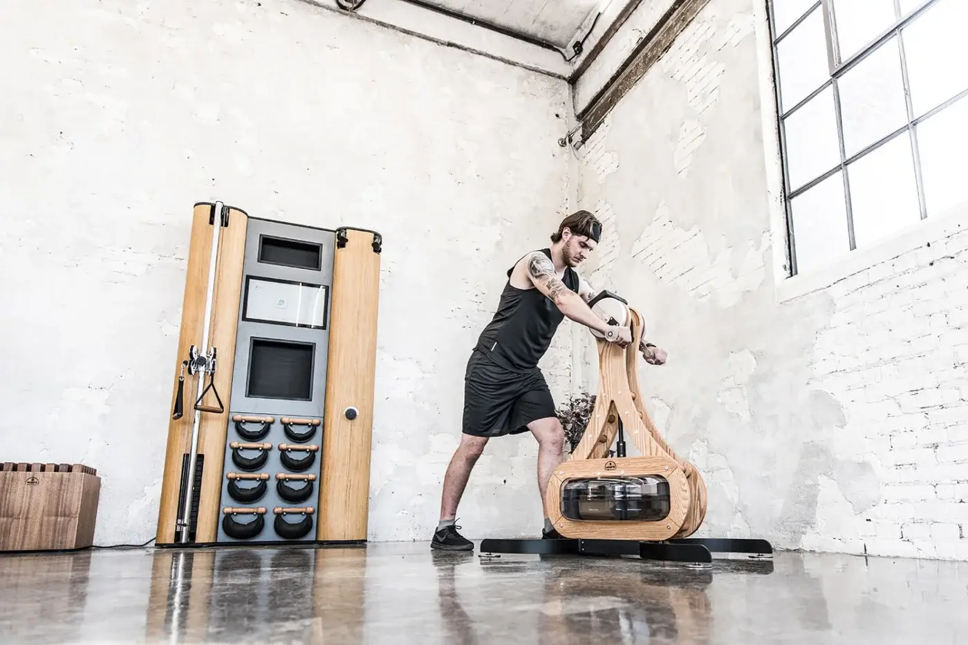 Waterrower Nohrd rowing machine, wood and acrylic, curved design in industrial gym with exposed brick and concrete floor.