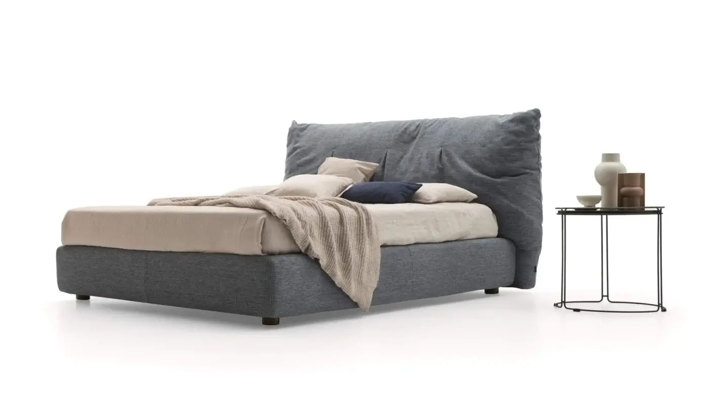Ditre Italia Papilo bed, gray fabric upholstery, low platform with oversized headboard, beige linen bedding, black metal side table.