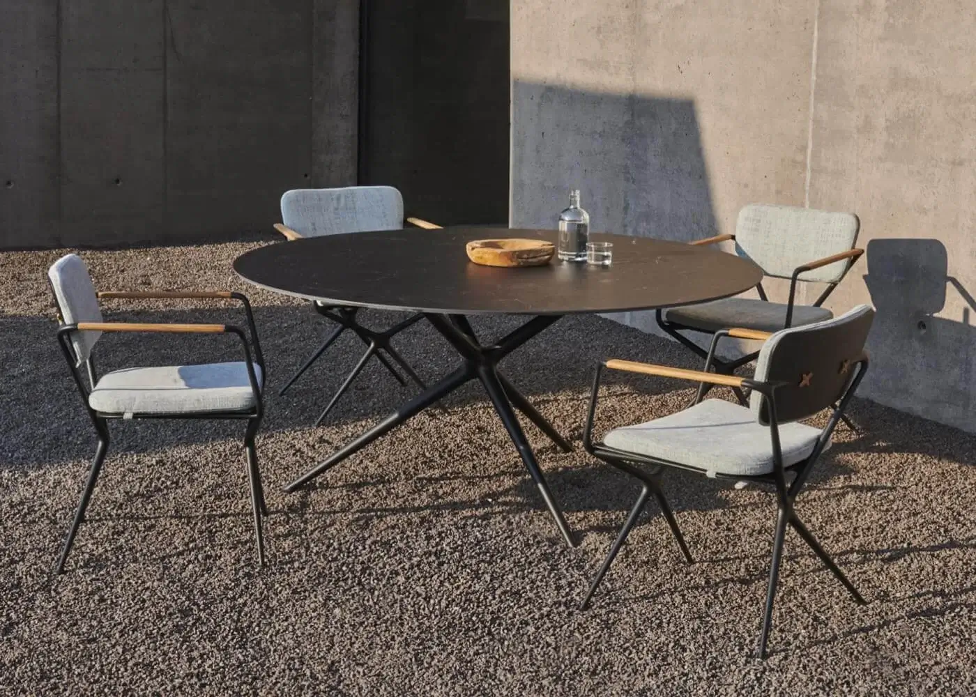Sophisticated Royal Botania Exes armchair with matte black cast aluminum frames and light gray textile seat built with tapered teak armrests