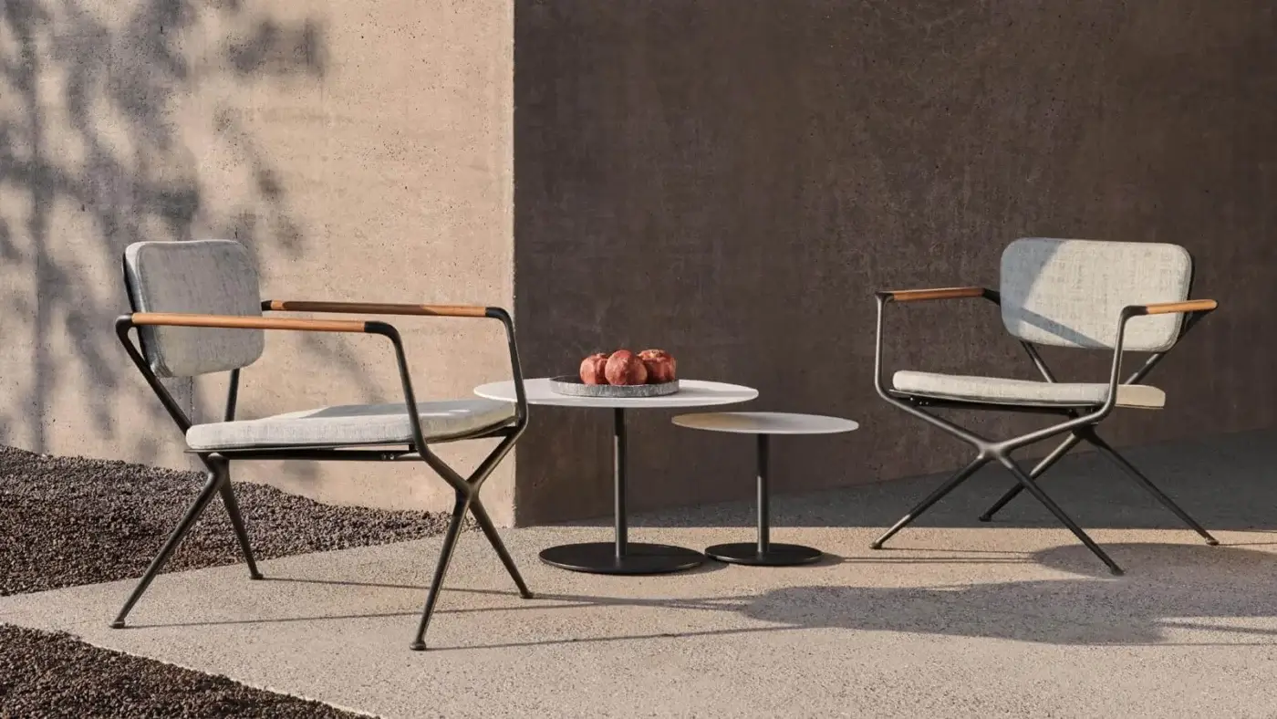 Superior Royal Botania Exes lounge chair with a light gray textile seat and black cast aluminum X frame built with tapered teak armrests