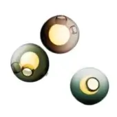 Wall lights, spherical shape, three colors: brown, dark green, pale blue-green; glossy finish, recessed circular details, warm internal glow.