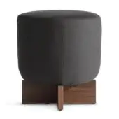 Cross ottoman, dark gray fabric upholstery, cylindrical shape with walnut crossed legs and visible wood grain, studio shot.