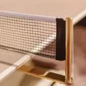 Vismara table tennis table, gold metal frame, black mesh net, white tabletop, polished finish, soft lighting, neutral background.