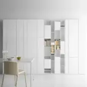White modular wall unit with rectangular panels, open shelving, and a white dining set with beige chair.