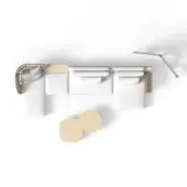 White sectional sofa with armchair, two beige sculptural forms, and gold wall lamp in a minimalist studio setting.
