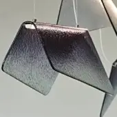 Trapezoidal pendant lights, fumé glass, blue-purple to silver gradient, suspended by silver wire, layered arrangement, neutral gray backdrop.