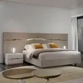 Neutral wall panel with a metallic line above a bed with light bedding and yellow pillows