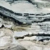 Layered stone surface with swirling bands of white, black, gray, beige, green, and brown, exhibiting a glossy, reflective, organic composition.
