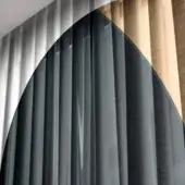 Curved partition with dark gray fabric, walnut wood panels, and brushed gray metal; text reads “lucido fume griaio lucido fume bronzo naturale”.