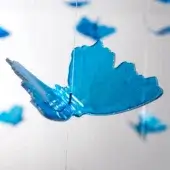 Blue resin butterfly mobile with textured surfaces, silver edges, and white cord suspension against a white wall.