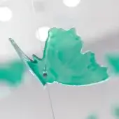 Leaf ornament, translucent turquoise glass, asymmetrical shape with silver metal frame and textured surface, minimalist design.