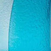 Textured wall with pale white stucco on left, vibrant turquoise plaster on right, divided by curved line, uneven granular surface.