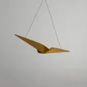 Suspension lamp, brushed gold metal, stylized bird shape with elongated wings and curved head, minimalist design against a light gray wall.