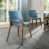 Harmonious Pacini & Cappellini Ellen chair with solid wood structure and curved, padded shell upholstered in smooth matte blue textile with medium brown finish