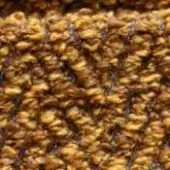Confectionery nougat texture, golden-brown spheres with dark strands, uneven surface, amber and caramel tones, granular close-up composition.