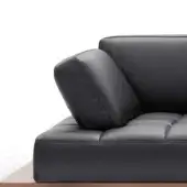 Black quilted leather modular sofa with square sections, angled back cushion, resting on dark walnut wood surface.