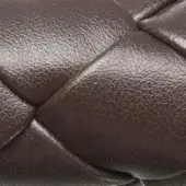 Dark brown braided texture, woven leather-like material with overlapping rounded segments, creating a granular, subtly three-dimensional surface.