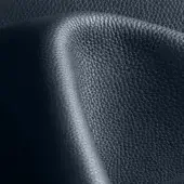 Dark blue pebbled leather texture with a diagonal fold, displaying a fine-grained, matte finish and subtle tonal variations under diffused lighting.