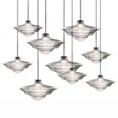 Pendant lights, clear rippled glass, shallow saucer shades with brushed brass fittings, arranged in staggered cluster against white backdrop.